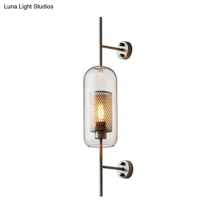 Modern black mesh wall mount lamp with a clear glass cylinder and amber honeycomb metal shade with brass hardware