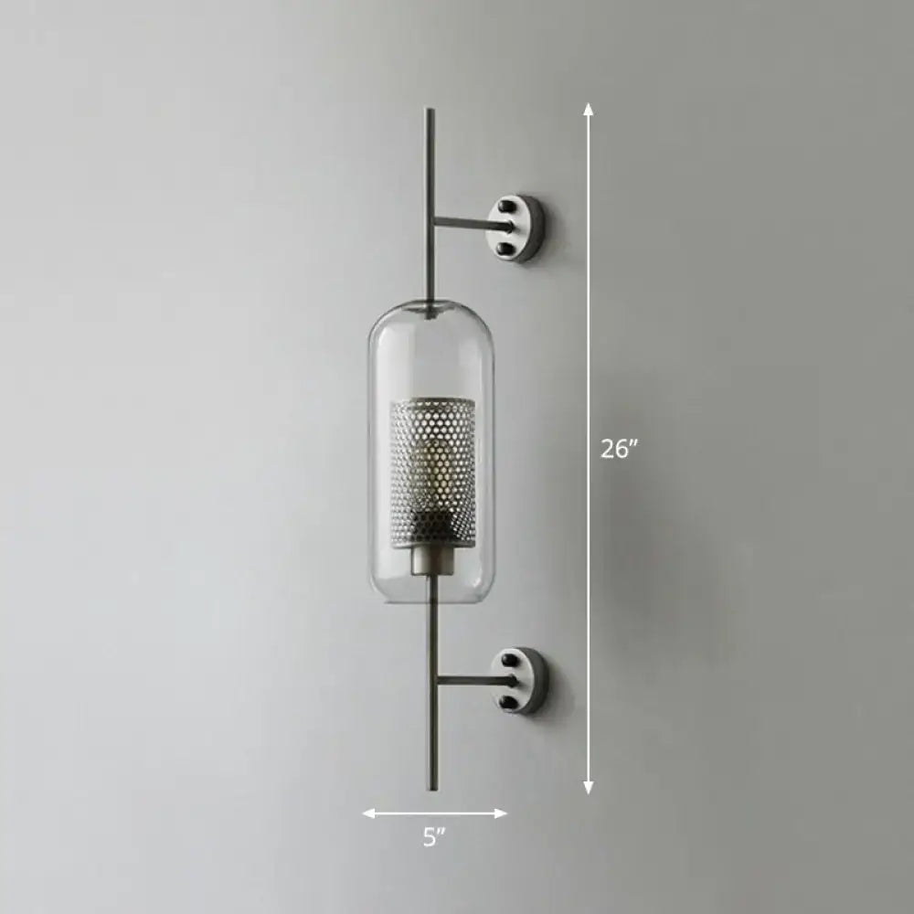 Modern black mesh wall mount lamp with clear glass cylinder and perforated metal interior on sleek black rods