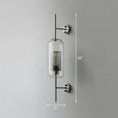 Modern black mesh wall mount lamp with clear glass cylinder and perforated metal interior on sleek black rods