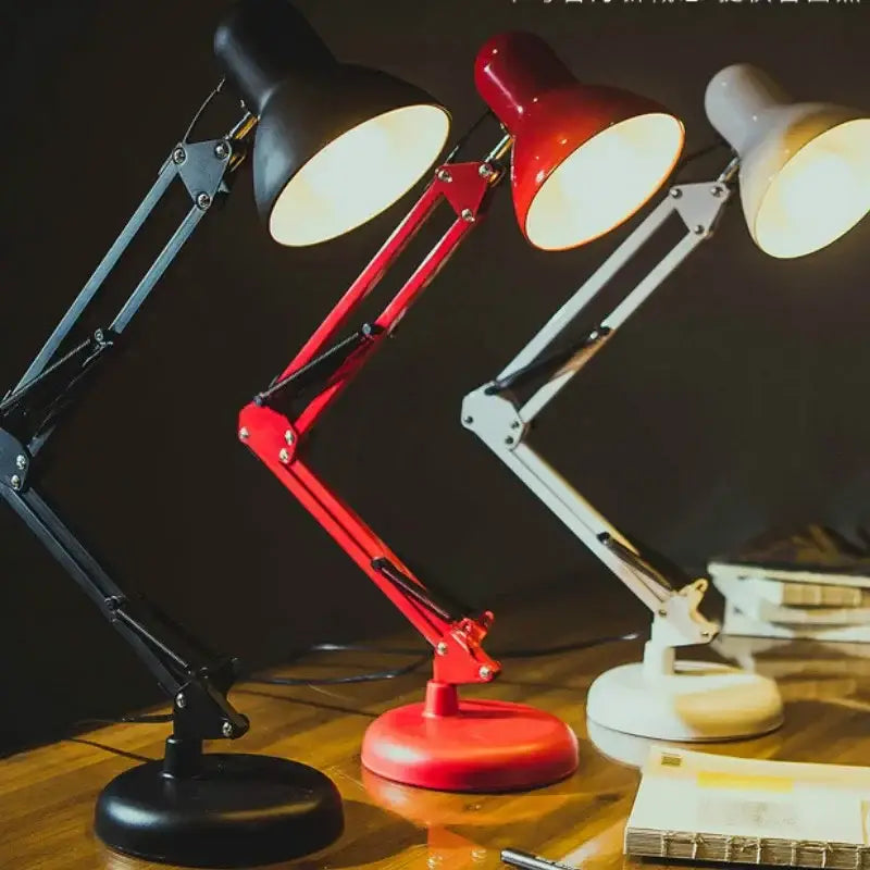 Three adjustable swing arm desk lamps in black red and white metal with circular bases for bedroom or office use