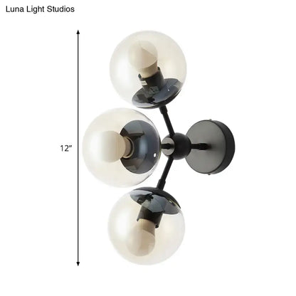 Modern black metal bathroom sconce featuring three clear glass spheres for elegant wall lighting