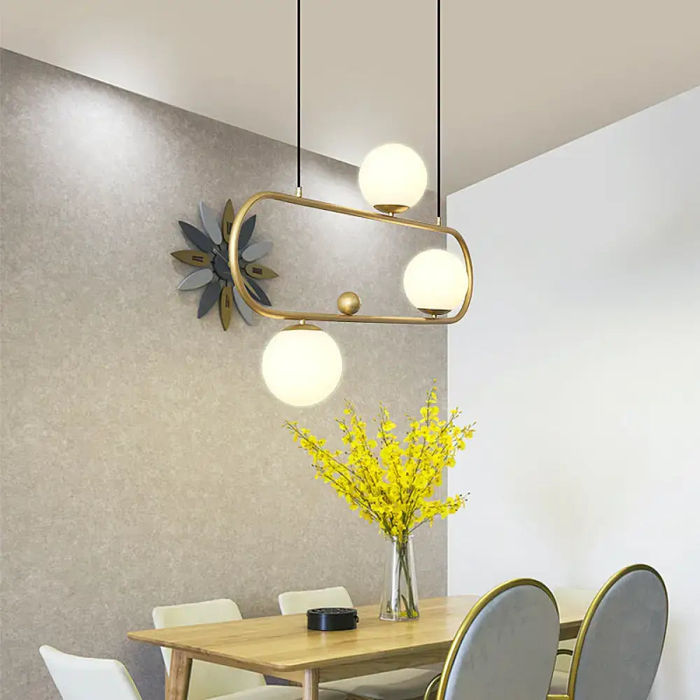 Modern brass-framed metal oblong island light fixture with three frosted milk glass globes by decorbites