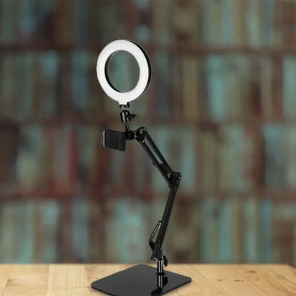 Black adjustable ring light with metal shade and smartphone mount on articulated arm for bedroom use