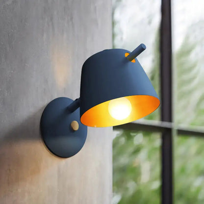 Modern black metal shade wall sconce with dark blue metal shade and warm orange interior for white blue bedroom light