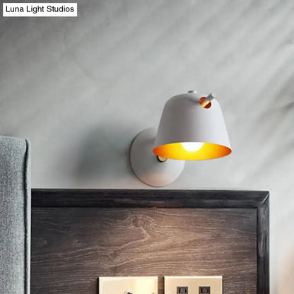 Modern black metal shade wall sconce with white ceramic and warm yellow glow featuring a small orange accent for bedroom use