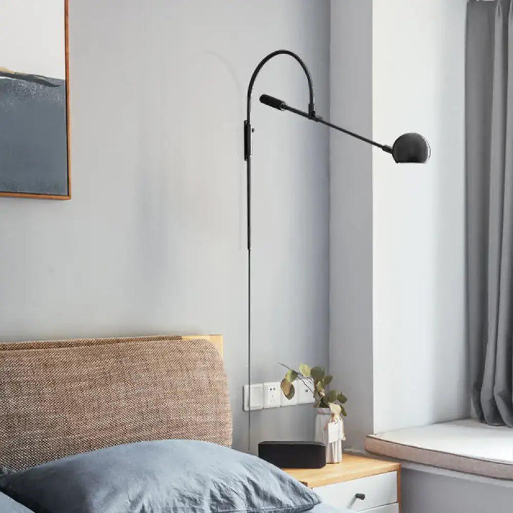 Modern black metal sphere wall sconce with curved arm and direct wired electric design for bedroom lighting