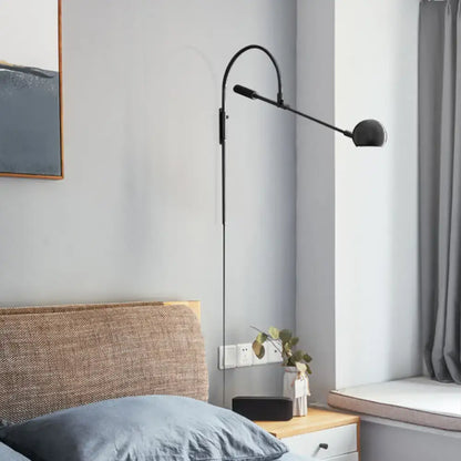 Modern black metal sphere wall sconce with curved arm and direct wired electric design for bedroom lighting