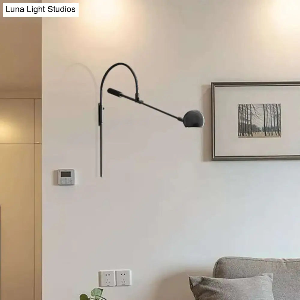 Modern black metal sphere wall sconce with curved arm and direct wired electric design for bedroom lighting