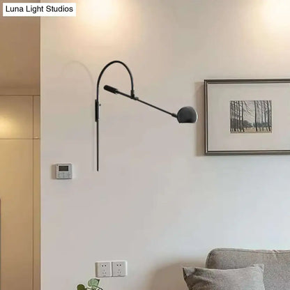 Modern black metal sphere wall sconce with curved arm and direct wired electric design for bedroom lighting
