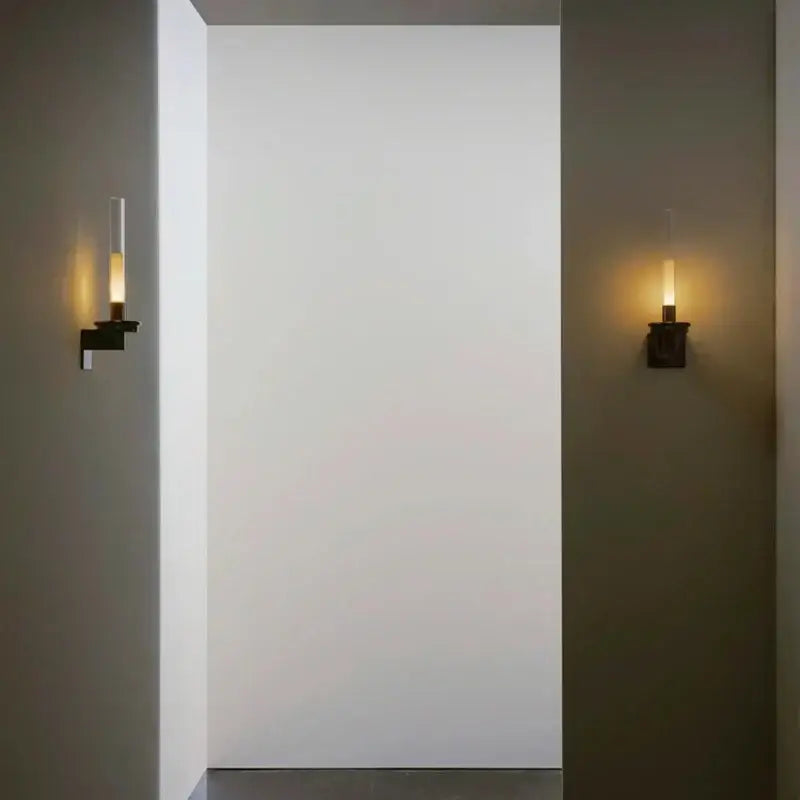 Modern black metal wall light with clear glass shade and warm glow designed for minimalist bedroom decor