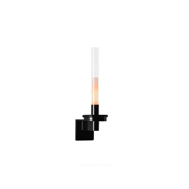 Modern black metal wall light featuring a clear glass cylindrical shade emitting warm light for bedroom use