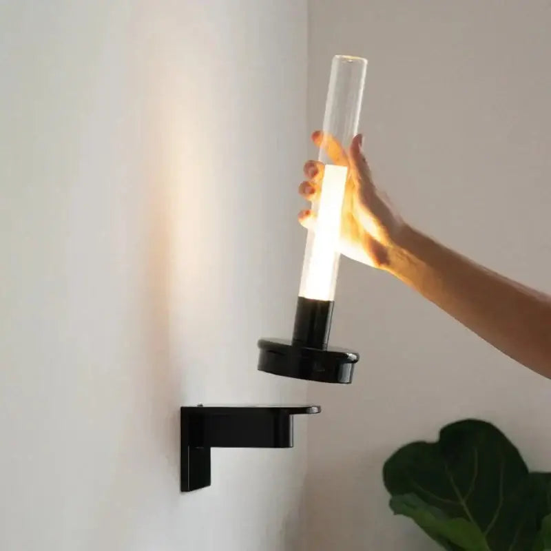 Modern black metal wall light with clear glass shade and cylindrical tube designed for bedroom lighting
