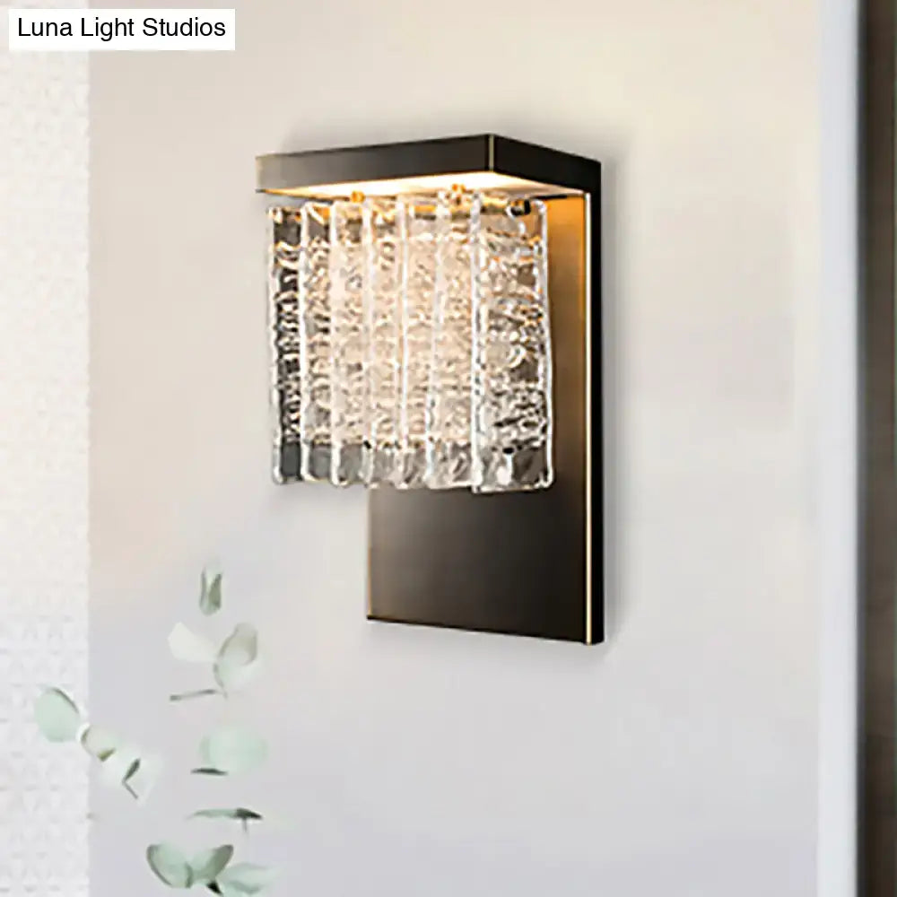 Modern black metal wall sconce with vertical crystal prism rods catching light in a living room 12 inch fixture