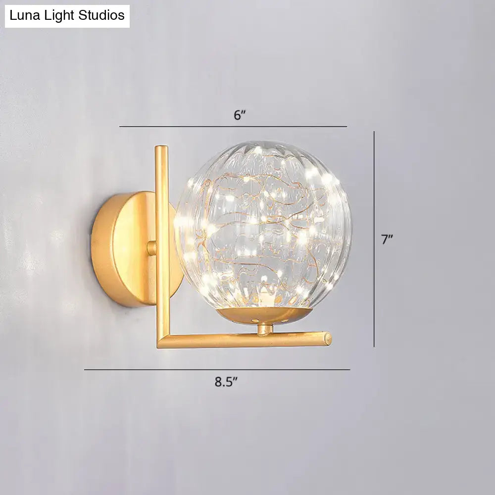Gold-toned mini globe wall sconce with textured glass globe and delicate string lights featuring compact fixture height