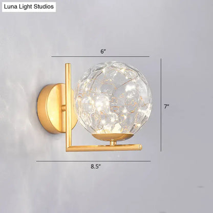 Gold-finished mini globe wall sconce with textured clear glass globe and internal led lighting fixture height ideal for bedrooms