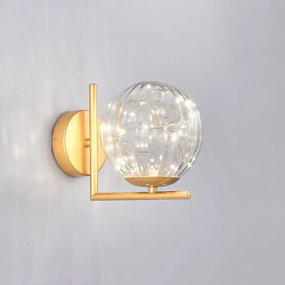 Gold-toned mini globe wall sconce with textured glass globe and delicate string lights for fixture height versatility