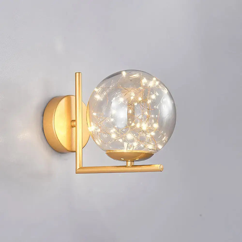 Gold-toned mini globe wall sconce with clear glass globe and delicate string lights, ideal for bedroom fixture height decor