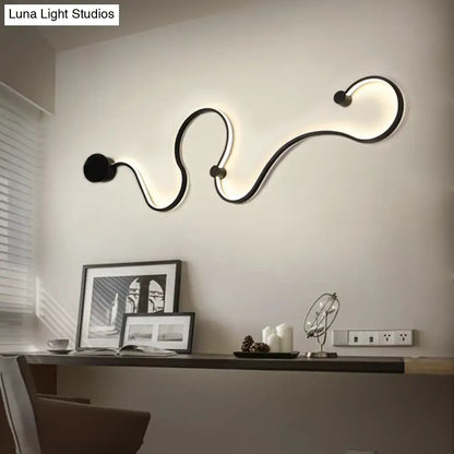 Modern black minimalist wall lamp with sleek curved design emitting white light for living room use