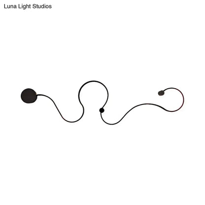 Modern black minimalist wall lamp with sleek curved lines and spherical accents emitting white light for living room use