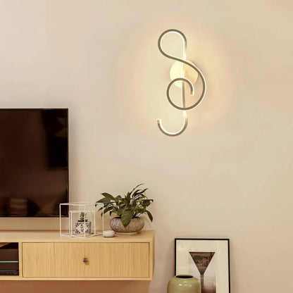 Modern black wall light with music note design in silver-toned metal emitting warm ambient led light for living room