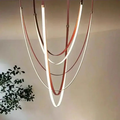 Modern black and orange leather belt pendant light with curved layered LED strips in warm white and copper for modern interiors