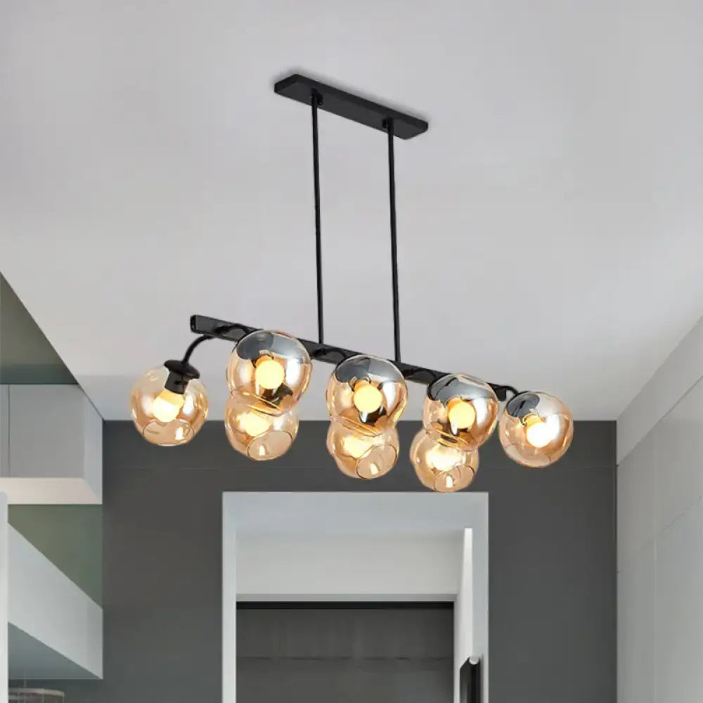 Modern black metal chandelier with five amber glass globe lights featuring a black orb shade for kitchen and dining room