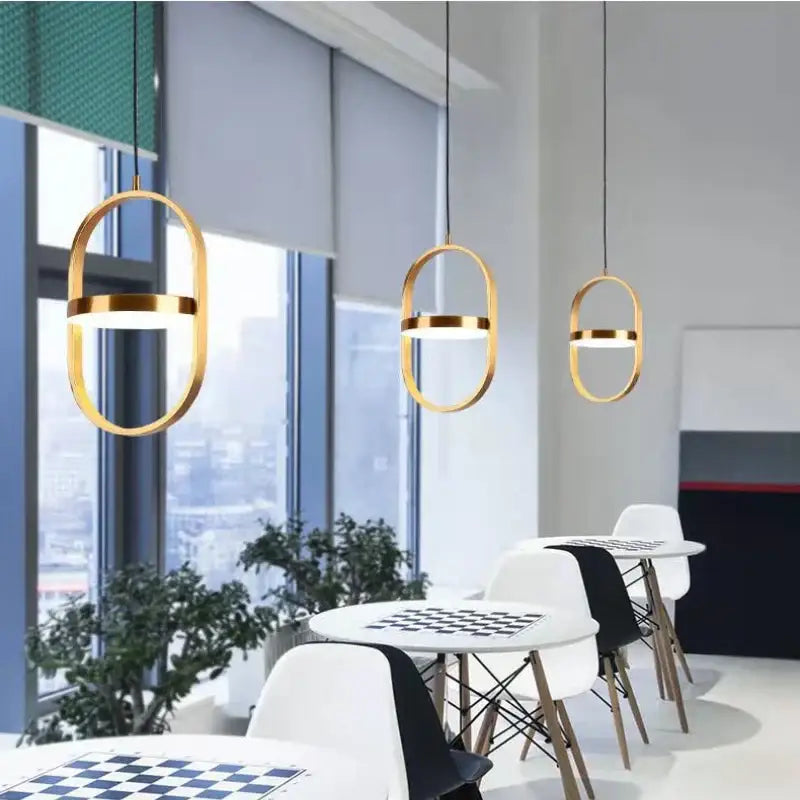 Three modern black oval decorbites adjustable angle pendant lights with gold frames and illuminated bands for kitchen decor