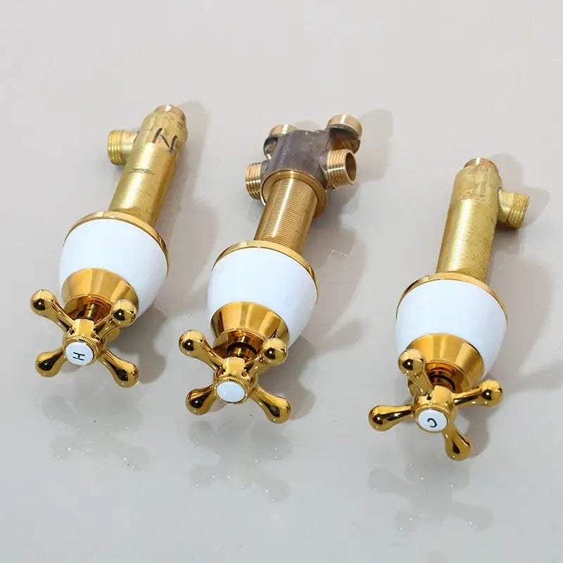 Three gold-finished bathroom faucets with white ceramic handles and cross knobs for black painting water control valve