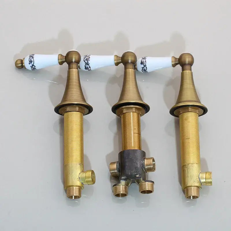 Three brass bathroom faucet handles with white ceramic knobs and blue floral patterns for black painting water control valve