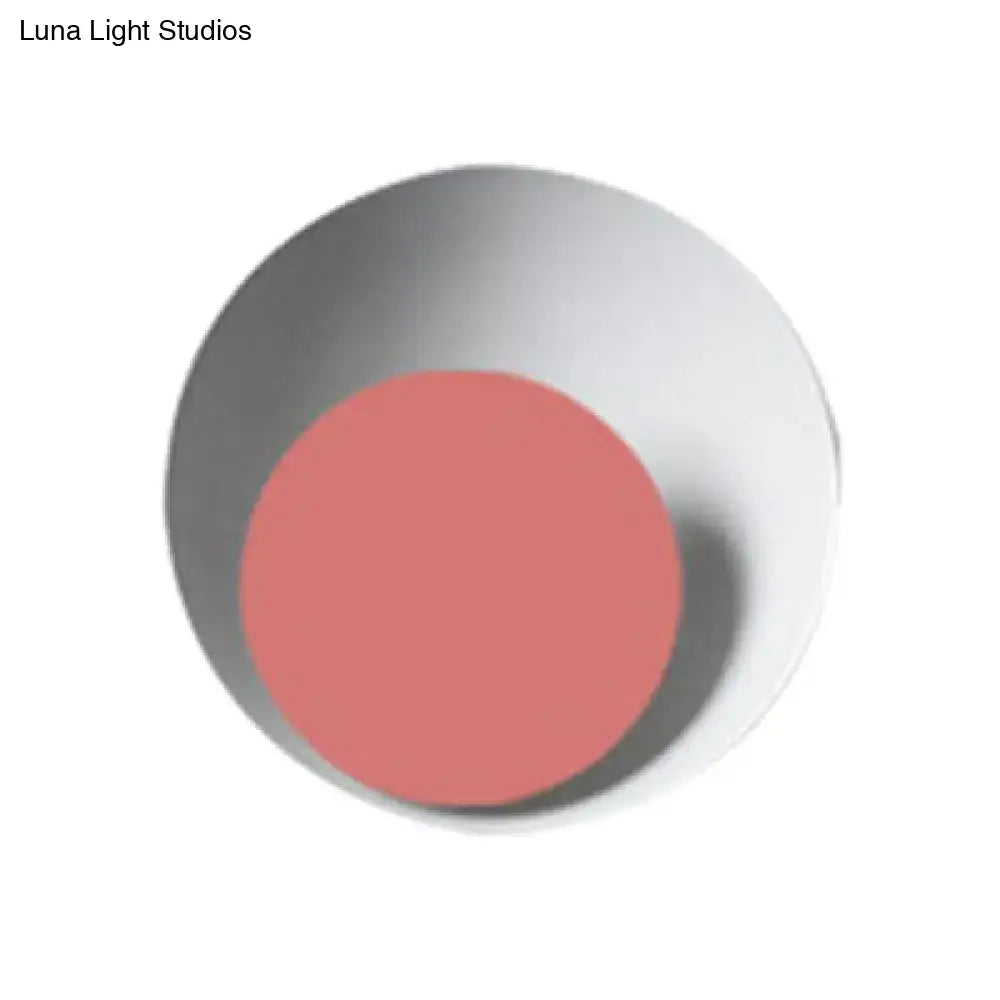 A modern black and pink circle sconce light fixture features a minimalist white ceramic bowl with a coral circle disc