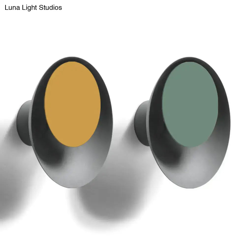 Modern oval-shaped wall hooks with matte black frame and vibrant mustard yellow and sage green circle sconce light fixture