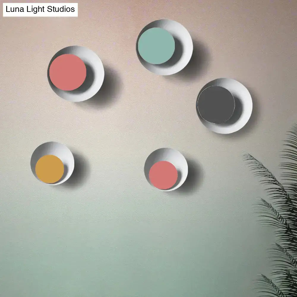 Set of five modern circle sconce lights with matte white metal frames and colorful disc inserts for bedroom use