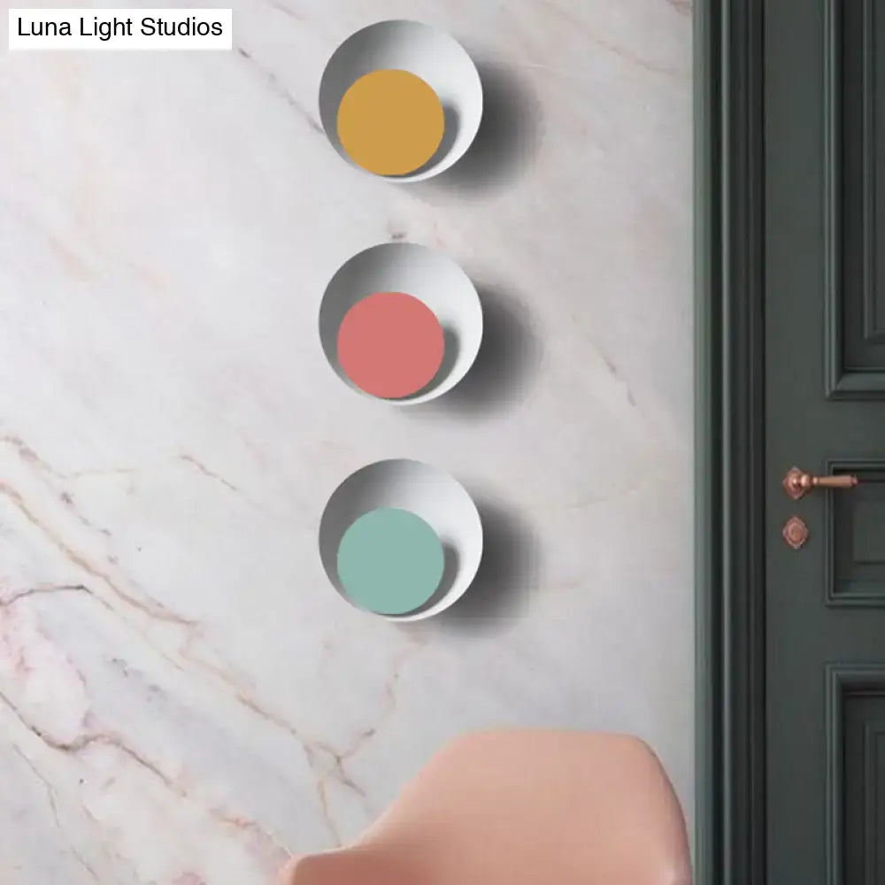 Modern black and pink circle sconce light fixture featuring three circular white ceramic rims with colored discs