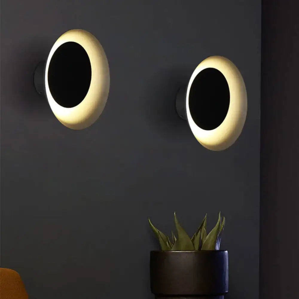 Modern black and pink circle sconce light fixture with warm glowing rings for bedroom wall decoration