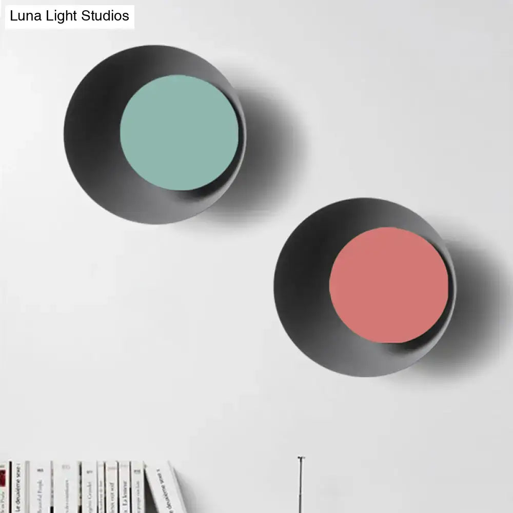 Modern black and pink circle sconce light fixture with matte black exterior and muted teal and soft coral interiors
