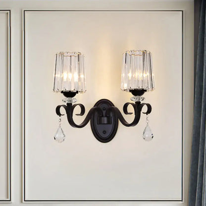 Modern black wrought iron wall mount lamp with two crystal candle-style shades and dangling teardrop crystals for living room
