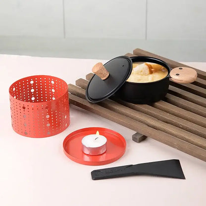 Modern black raclette fondue set with wooden lid and handle showing a creamy dish in a black pot for dining room grill