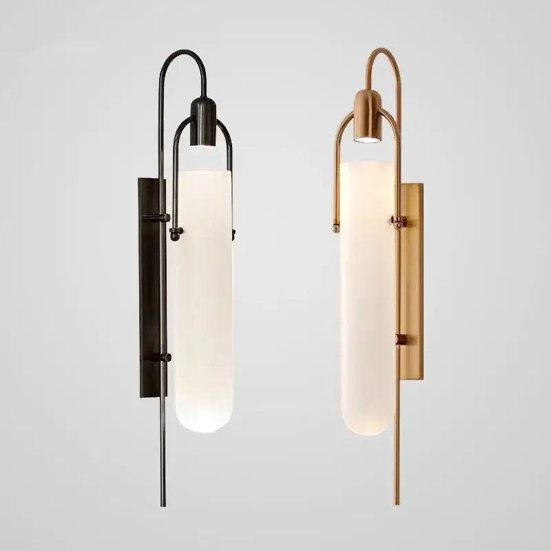 Two modern wall lamp sconces with matte black and brushed brass metal frames and tall frosted glass shade led cylinders