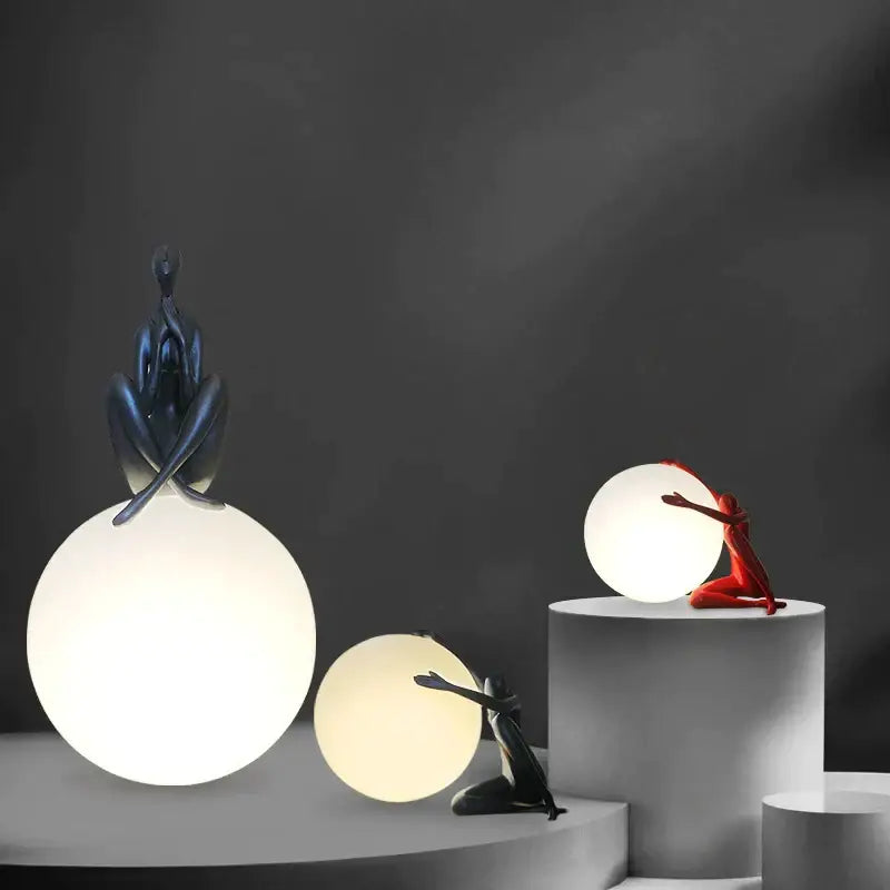 Modern black and red abstract humanoid ball holder table lamp featuring sculptural figurines for bedroom decorbites decor