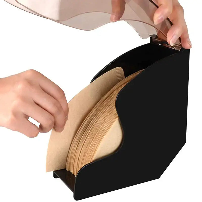 Modern black and rose gold wave coffee filter dispenser with clear lid and beige paper coffee filters inside