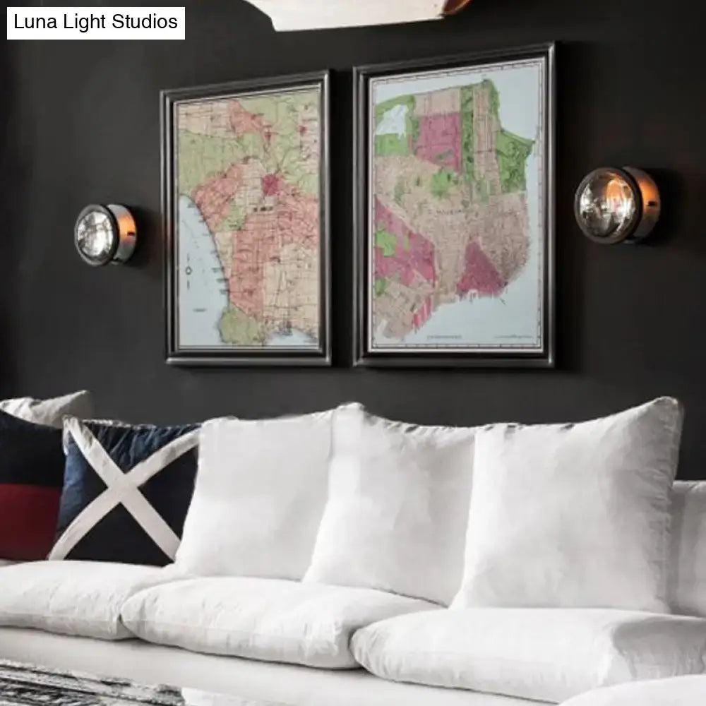 Modern black round wall sconce with e12 e14 bulb base shown near two framed vintage maps in sleek black frames