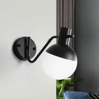 Modern black sconce light with black matte finish curved arm and spherical global milk glass shade for living room