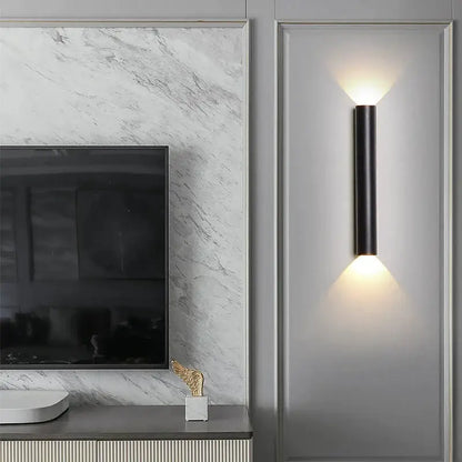 Modern black cylindrical led wall lamp with silver accents and warm up and down lighting for bedroom use