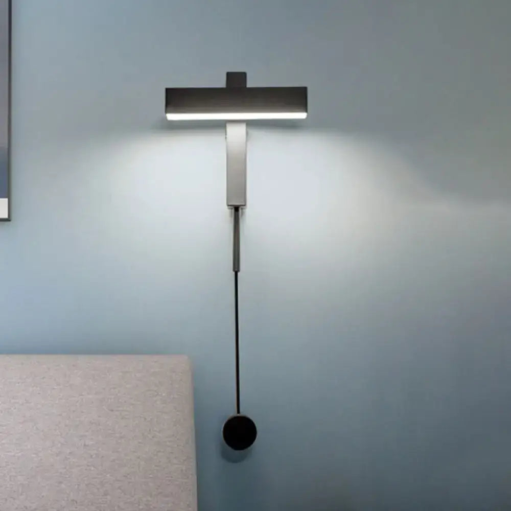 Modern black and silver wall lamp with adjustable arm, sleek metallic finish, elongated light head, and bulb base details