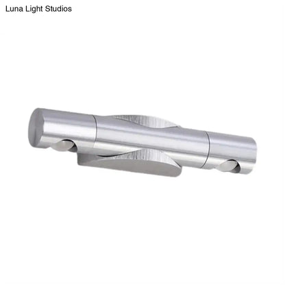 Silver metallic wall-mounted light fixture with two cylindrical arms and warm white lighting for living room use