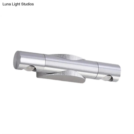 Silver metallic wall-mounted light fixture with two cylindrical arms and warm white lighting for living room use