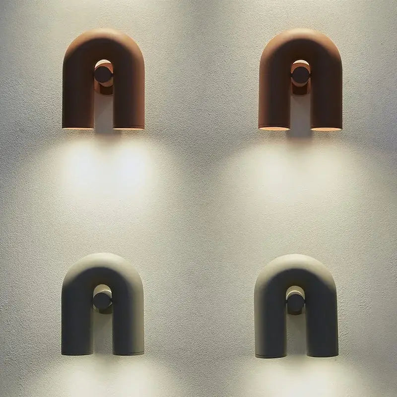 Two minimalist u-shaped tube wall lamps in terracotta and matte gray ceramic with central circular accents for bedrooms