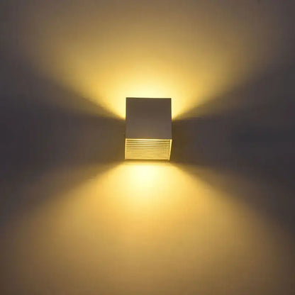 Modern black square 12w cob led wall lamp with matte white and brushed metallic design emitting warm yellow light