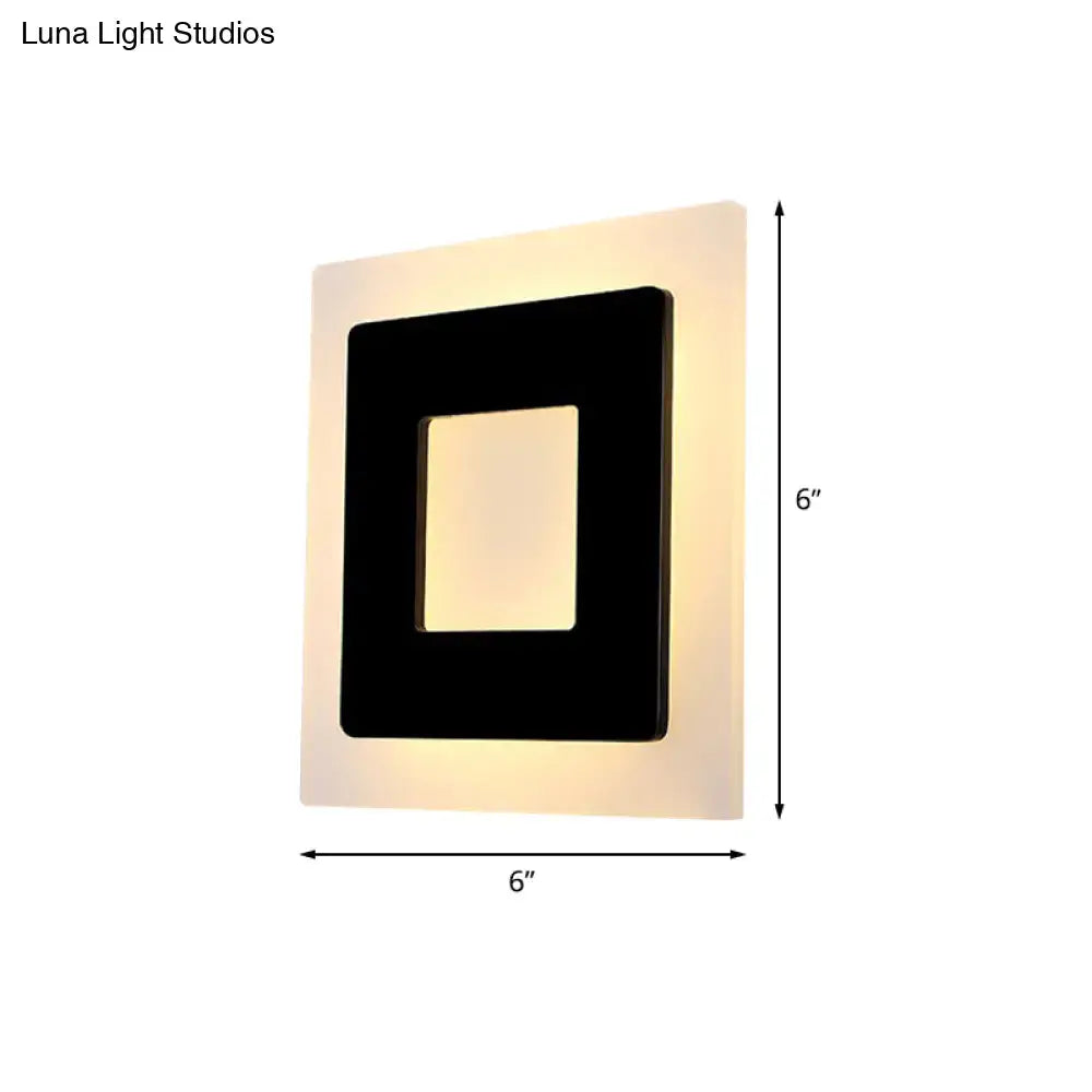 Modern black square sconce light with a black inner frame emitting warm light, ideal for bedroom use