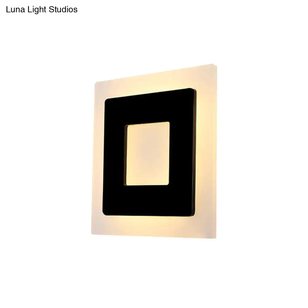Modern black square sconce light with a sleek frame providing warm light for bedroom illumination